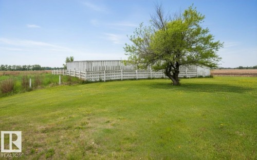 Expansive green lawn featuring a mature deciduous tree, white perimeter fencing, and open field surroundings - 60230 Rg Rd 271, Rural Westlock County, AB 