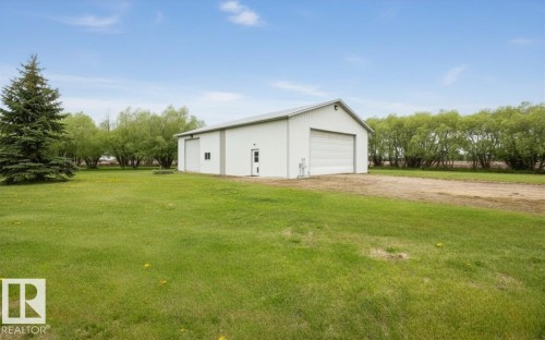 White metal-sided outbuilding featuring a pitched roof and multiple large roll-up doors - 60230 Rg Rd 271, Rural Westlock County, AB 