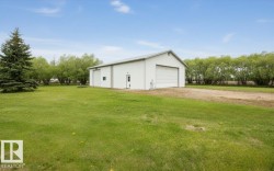 White metal-sided outbuilding featuring a pitched roof and multiple large roll-up doors - 