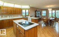 Kitchen featuring wood cabinetry, white countertops, and an island with a built-in cooktop - 
