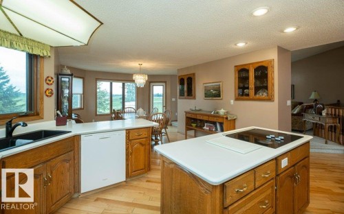 Kitchen featuring wood-finish flooring, oak cabinetry, white countertops, and a black double basin sink - 60230 Rg Rd 271, Rural Westlock County, AB 