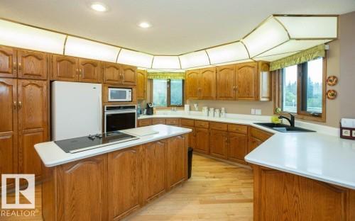 Expansive kitchen featuring wood cabinetry, light countertops, an integrated cooktop on the island, a built-in oven, and recessed lighting - 60230 Rg Rd 271, Rural Westlock County, AB 