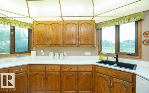 Kitchen featuring wood cabinetry, white countertops, a black double-basin sink with a matte black faucet, and large windows - 60230 Rg Rd 271, Rural Westlock County, AB 