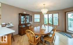 Dining area with wood-finish flooring, a contemporary chandelier, large windows, and direct access to an exterior deck - 