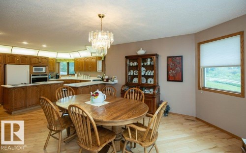 Dining area featuring wood-finish flooring, a contemporary chandelier, and a bay window with exterior views - 60230 Rg Rd 271, Rural Westlock County, AB 