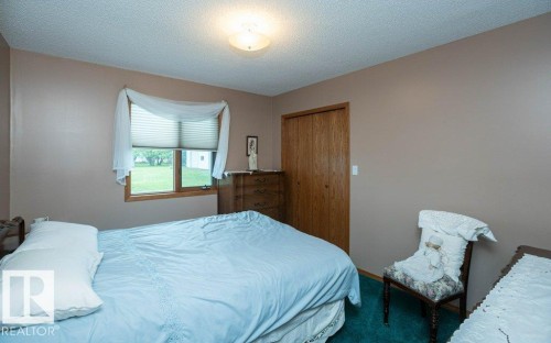 Interior room featuring a window with wood-finish trim, a flush-mount ceiling light fixture, and wood-finish bi-fold doors - 60230 Rg Rd 271, Rural Westlock County, AB 