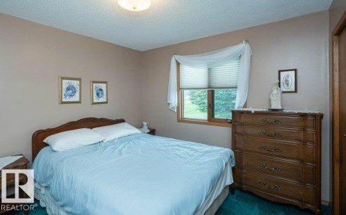 Carpeted room with a ceiling-mounted light fixture, light-toned walls, and a window with blinds and wood trim - 60230 Rg Rd 271, Rural Westlock County, AB 