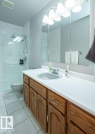 Bathroom featuring a wood-finish vanity with a white countertop and an integrated sink - 