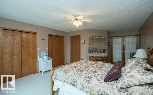 Spacious room featuring light-colored carpeting, multiple wood-finish closet doors, and a ceiling fan with integrated lighting - 60230 Rg Rd 271, Rural Westlock County, AB 