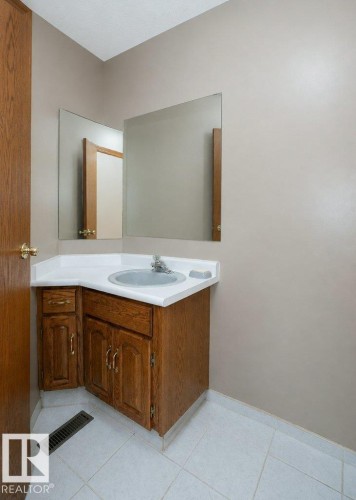 Corner vanity with wood-finish cabinetry, white countertop, and integrated sink - 60230 Rg Rd 271, Rural Westlock County, AB 
