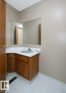 Corner vanity with wood-finish cabinetry, white countertop, and integrated sink - 