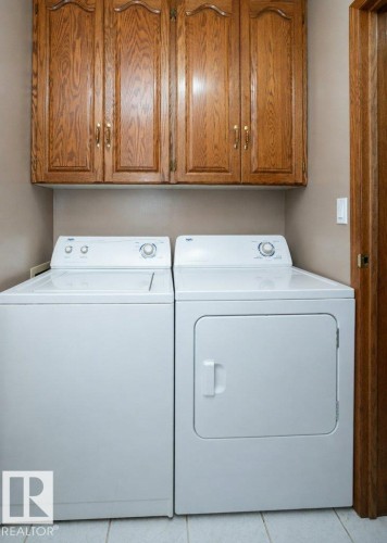Dedicated laundry area featuring overhead wood cabinetry with decorative paneling and brass hardware - 60230 Rg Rd 271, Rural Westlock County, AB 