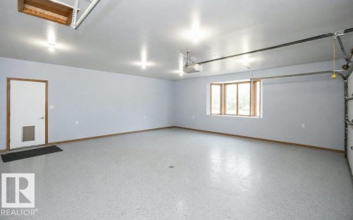 Spacious garage with light gray walls, an epoxy-coated concrete floor, and multiple recessed ceiling lights - 60230 Rg Rd 271, Rural Westlock County, AB 