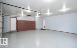 Spacious garage featuring a durable epoxy floor finish, recessed ceiling lighting, extensive built-in storage cabinetry, and two access doors - 