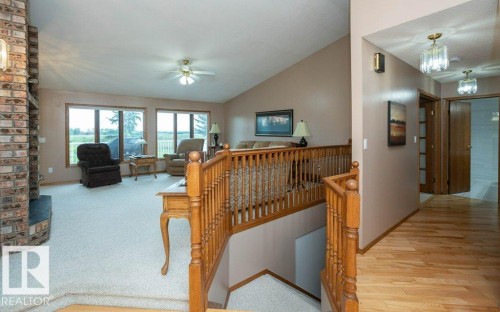 Spacious living area featuring a vaulted ceiling and brick-clad fireplace - 60230 Rg Rd 271, Rural Westlock County, AB 
