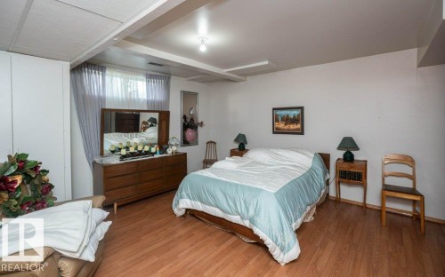 Spacious interior featuring wood-finish flooring, a window with curtains, and a white ceiling with exposed beams - 60230 Rg Rd 271, Rural Westlock County, AB 