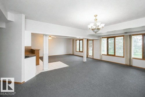 Spacious room featuring extensive window-framed glass, a brass and glass chandelier, recessed lighting, and grey carpeting - 60230 Rg Rd 271, Rural Westlock County, AB 
