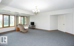 Room featuring light gray carpeting, white walls, and wood-trim windows - 