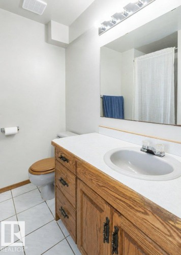 Bathroom featuring a wood-finish vanity with a white countertop, an integrated sink, and a large wall-mounted mirror - 60230 Rg Rd 271, Rural Westlock County, AB 