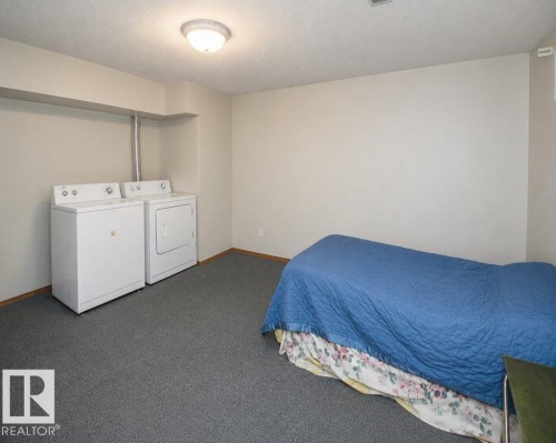 Dedicated laundry area featuring a white washing machine and dryer, accompanied by soft grey carpeting - 60230 Rg Rd 271, Rural Westlock County, AB 