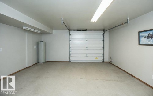 Attached garage featuring a white sectional door, concrete flooring, and ceiling-mounted fluorescent lighting - 60230 Rg Rd 271, Rural Westlock County, AB 