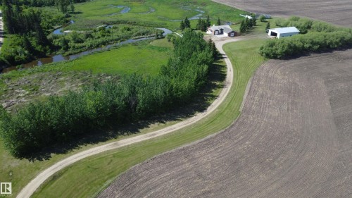Expansive property featuring a winding gravel driveway, a residential structure with an attached garage, and a large outbuilding - 60230 Rg Rd 271, Rural Westlock County, AB 