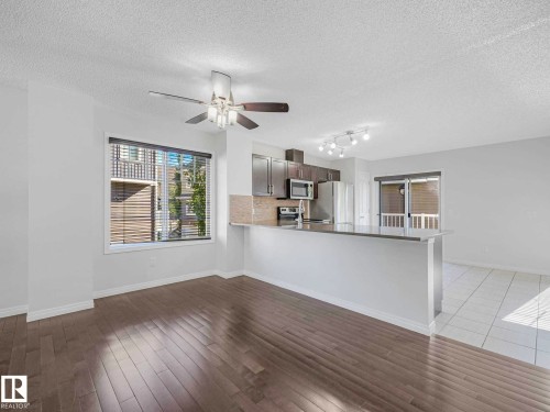 Open-concept living space featuring wood-finish flooring, a ceiling fan with integrated lighting, and a window with blinds - 77 4050 Savaryn Drive, Edmonton, AB 
