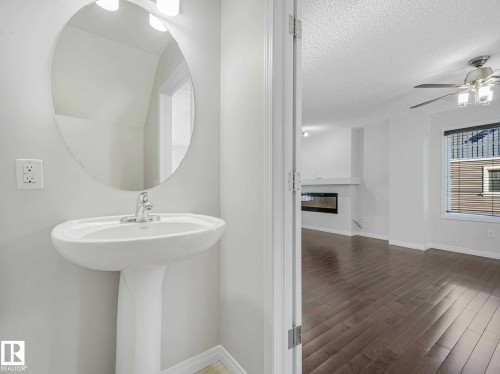 White pedestal sink with chrome faucet and oval mirror - 77 4050 Savaryn Drive, Edmonton, AB 