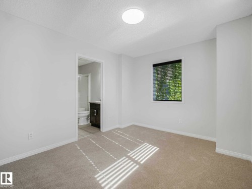 Bright room featuring neutral carpeting and white baseboards - 77 4050 Savaryn Drive, Edmonton, AB 