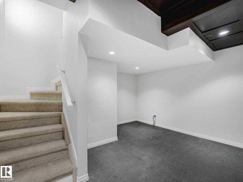Carpeted staircase with white handrail and trim - 77 4050 Savaryn Drive, Edmonton, AB 