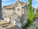 Contemporary multi-level townhome featuring a two-tone siding exterior, attached garage, private balcony, and mature landscaping - 77 4050 Savaryn Drive, Edmonton, AB 