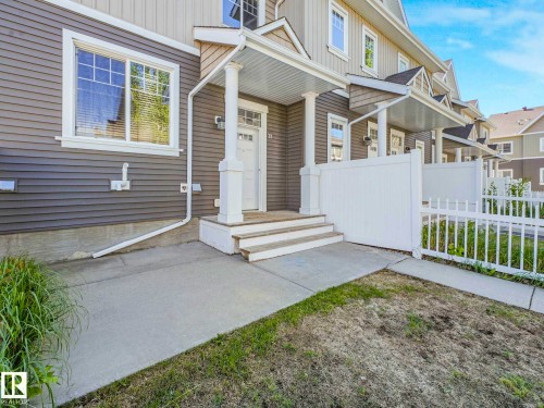 Grey horizontal siding with white trim and a covered front entry - 77 4050 Savaryn Drive, Edmonton, AB 