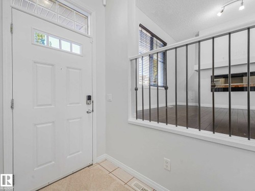 Entryway featuring a panel door with transom windows and a smart lock, complemented by tile flooring - 77 4050 Savaryn Drive, Edmonton, AB 