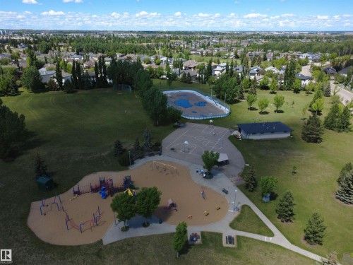 Expansive recreational park featuring a large sand-based playground, a multi-sport court, a dedicated rink area, and a green space bordered by mature trees - 915 Picard Drive Nw, Edmonton, AB 