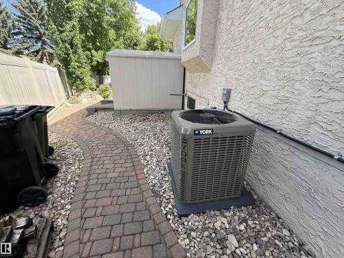Exterior side yard featuring a new HVAC unit, stucco siding, and a paver pathway - 915 Picard Drive Nw, Edmonton, AB 