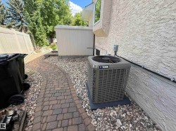 Exterior side yard featuring a new HVAC unit, stucco siding, and a paver pathway - 