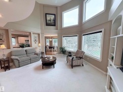 Two-story living area with high ceilings, multiple large windows, and an open concept layout - 