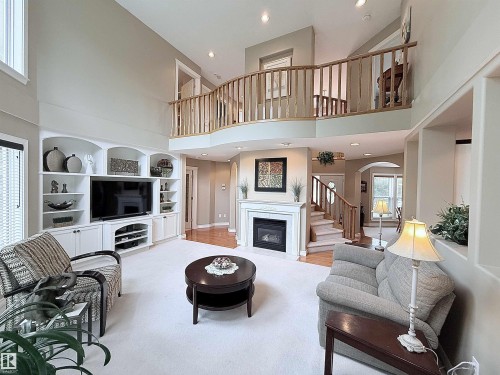 Vaulted living room featuring a second-story overlook, built-in entertainment center, fireplace with mantel, and staircase with wood railing - 915 Picard Drive Nw, Edmonton, AB 