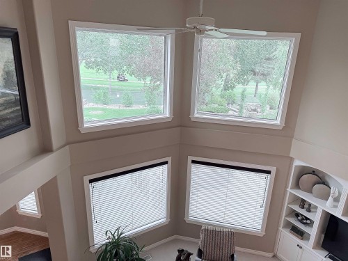 Two-story interior with a ceiling fan, multiple windows with white trim, and a built-in shelving unit - 915 Picard Drive Nw, Edmonton, AB 