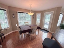 Dining area featuring wood-finish flooring and a central pendant light fixture - 
