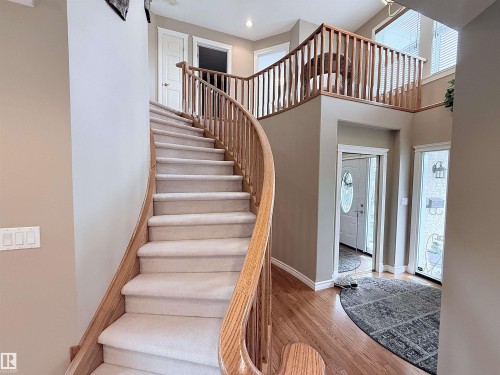 Curved staircase featuring carpeted treads and natural wood handrails - 915 Picard Drive Nw, Edmonton, AB 