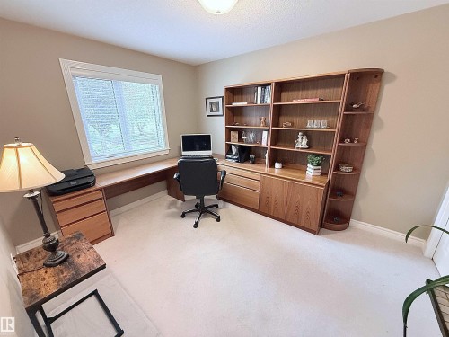 Integrated wood-finish desk with a built-in shelving unit featuring open and closed storage - 915 Picard Drive Nw, Edmonton, AB 