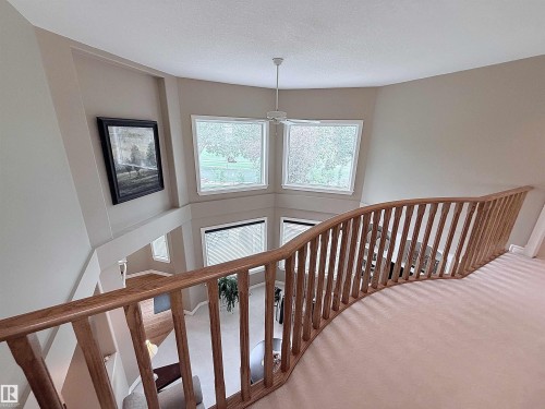 Open concept mezzanine overlooking a lower level, featuring a natural wood railing, vaulted ceiling, and multiple transom windows - 915 Picard Drive Nw, Edmonton, AB 
