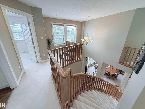 Multi-level interior featuring a carpeted curved staircase with wood railing and balusters - 915 Picard Drive Nw, Edmonton, AB 