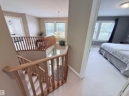 Multi-level interior featuring a carpeted staircase with wood railings and balusters, transom windows, and a chandelier lighting fixture - 915 Picard Drive Nw, Edmonton, AB 