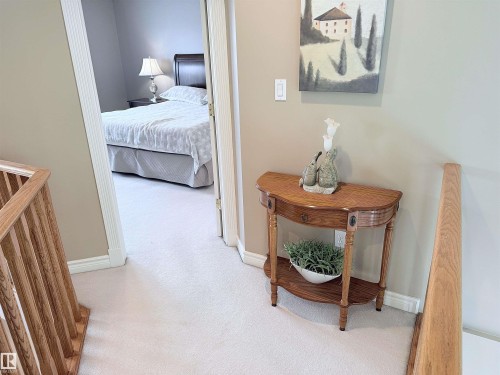 Carpeted hallway featuring wood stair railings, a neutral wall color, and white trim - 915 Picard Drive Nw, Edmonton, AB 