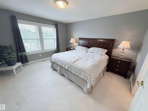 Spacious room featuring light-colored carpeting, a large window with blinds, and neutral grey wall paint - 915 Picard Drive Nw, Edmonton, AB 