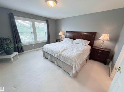 Spacious room featuring light-colored carpeting, a large window with blinds, and neutral grey wall paint - 