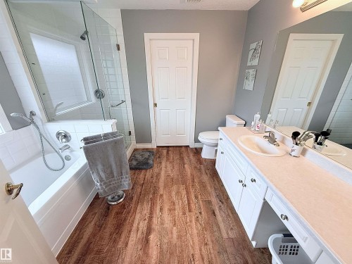 Bathroom with wood-finish flooring, a white vanity with an integrated sink, and a combination tub and shower - 915 Picard Drive Nw, Edmonton, AB 