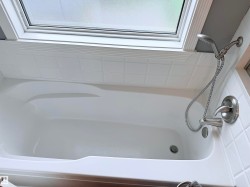 White bathtub with brushed nickel shower fixtures and a handheld spray - 